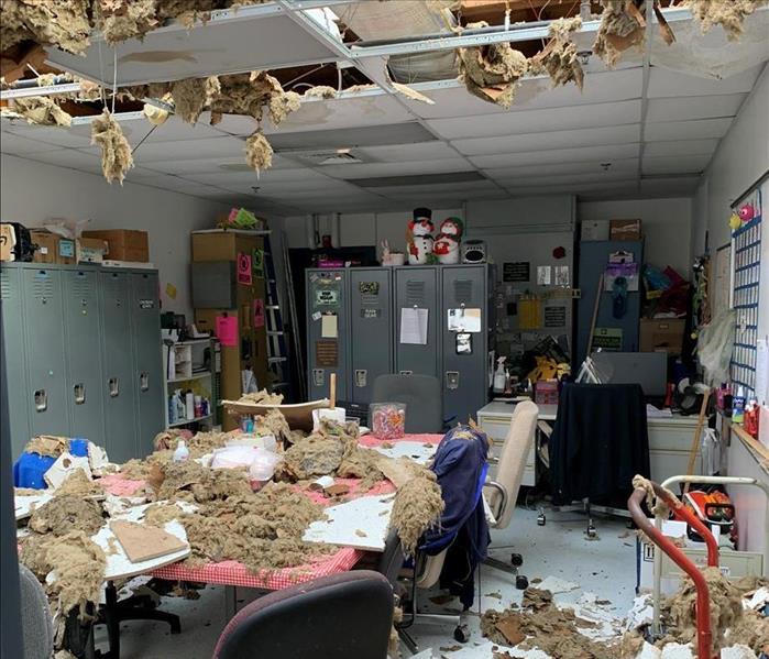 Damage to a school after a tornado came through.  Entire roof torn off, ceiling tiles and insulation scattered in classroom.