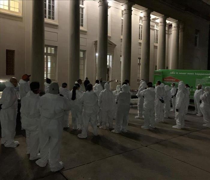 Servpro employees line up with white tyvek suits on for a commercial customer.