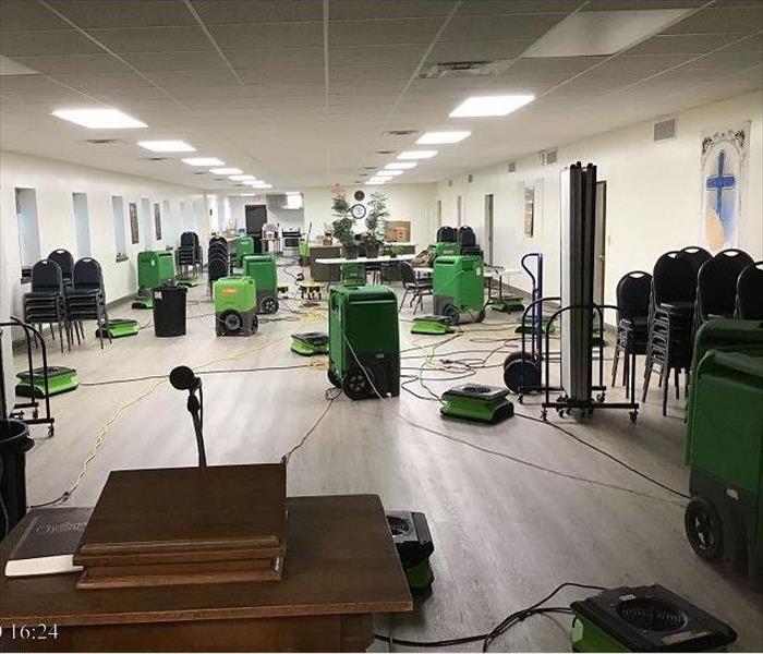Servpro green dehumidifiers and air movers within a lecture hall impacted by water.