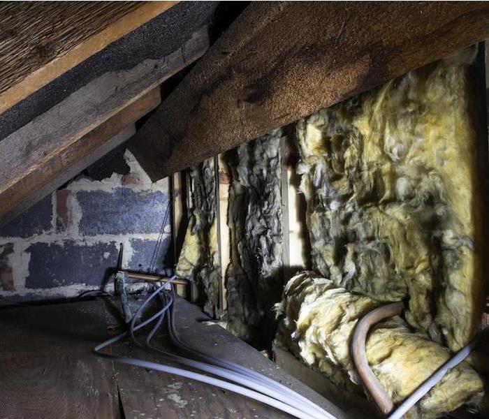 "a dark crawl space showing signs of water damage on insulation